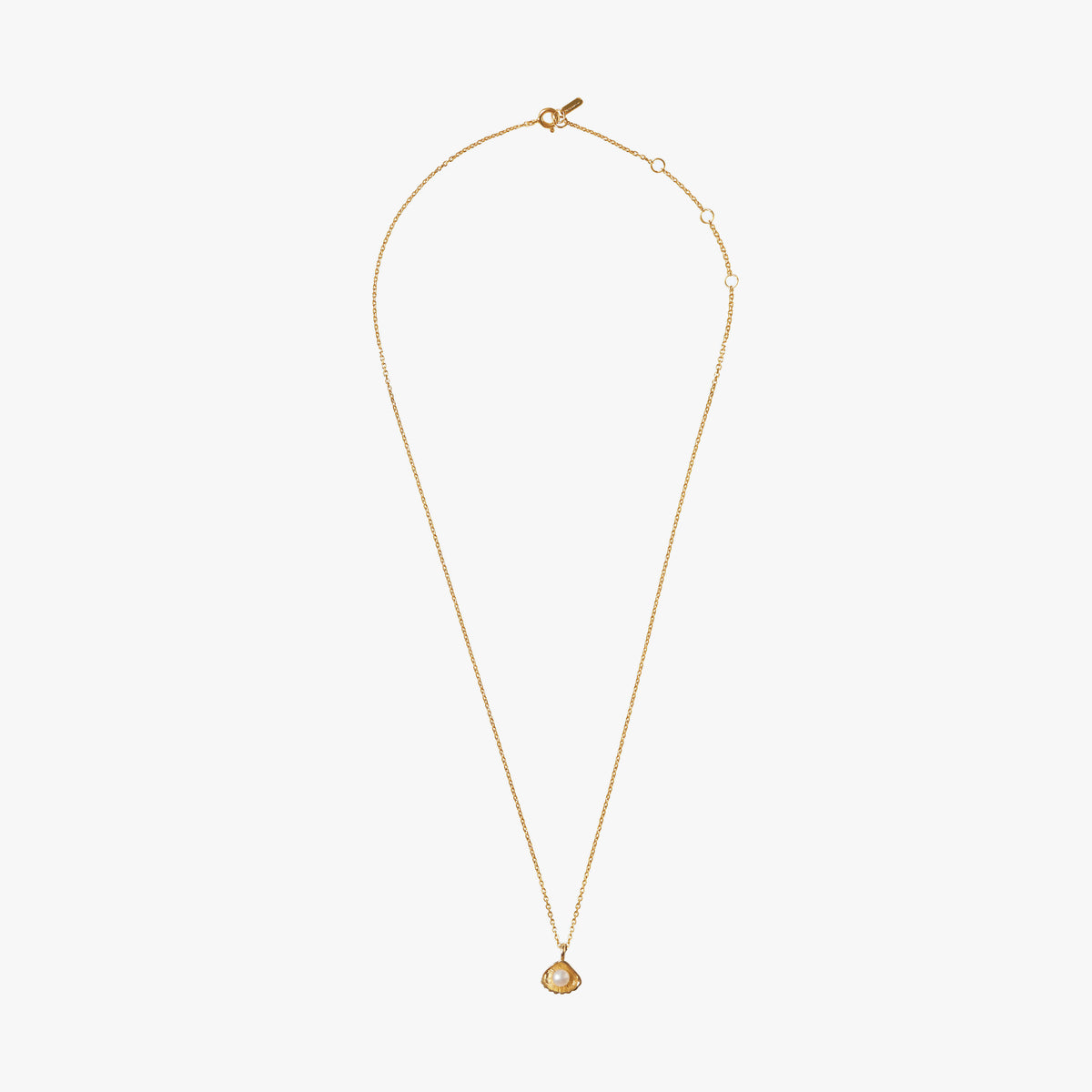 Close-up of Flacq gold necklace featuring a white freshwater pearl and sculptural shell pendant