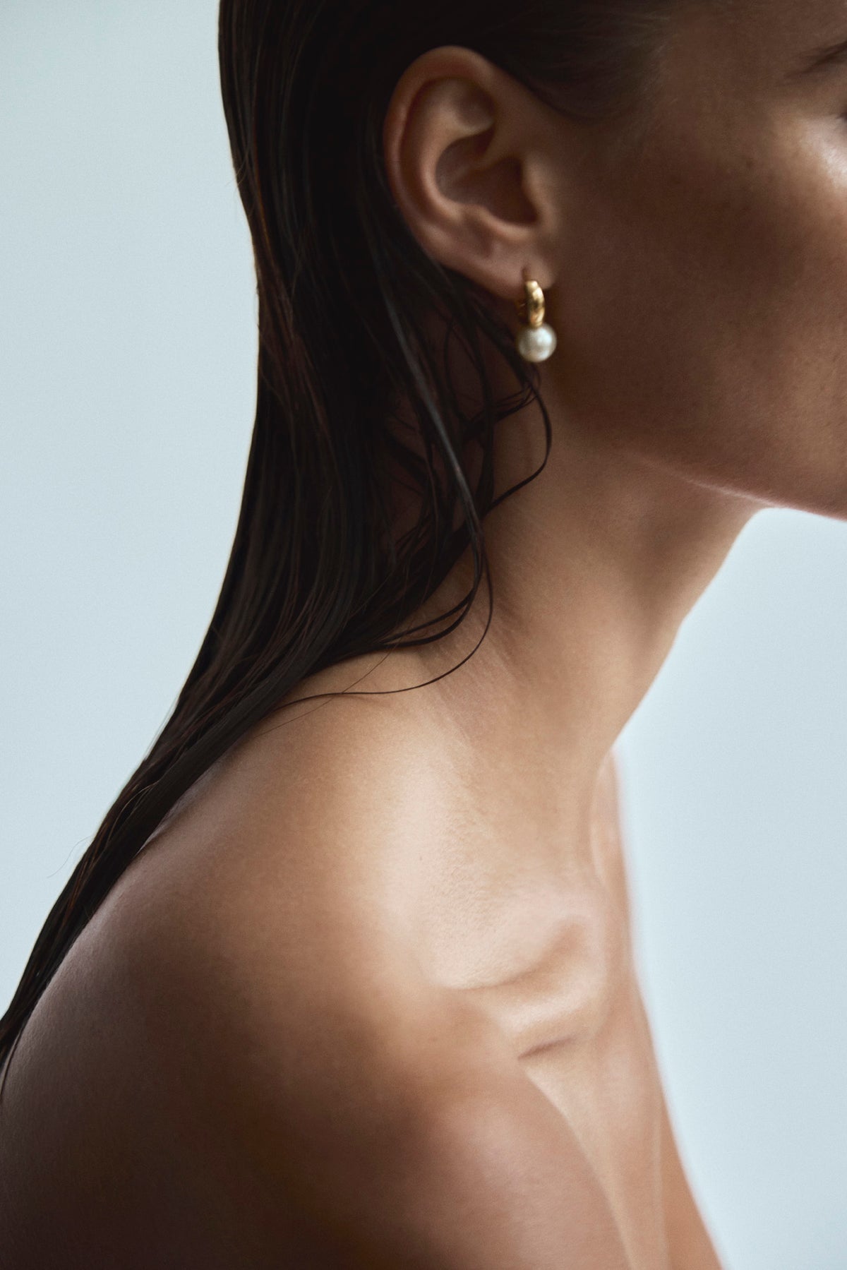 Side view of Rivière des Créoles gold round pearl hoop earrings
