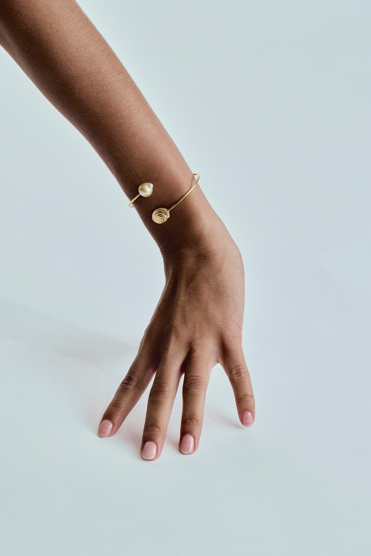 18K solid gold Trou D’Eau Douce bracelet with white South Sea pearl and spiral shell detail on wrist