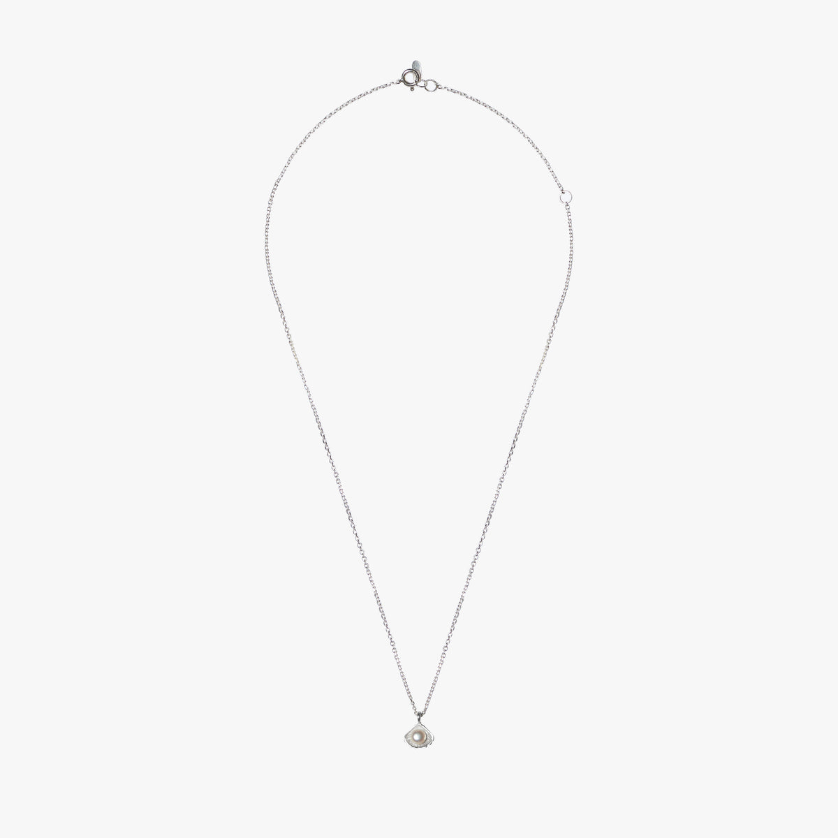 Close-up of Flacq silver necklace featuring a white freshwater pearl and sculptural shell pendant