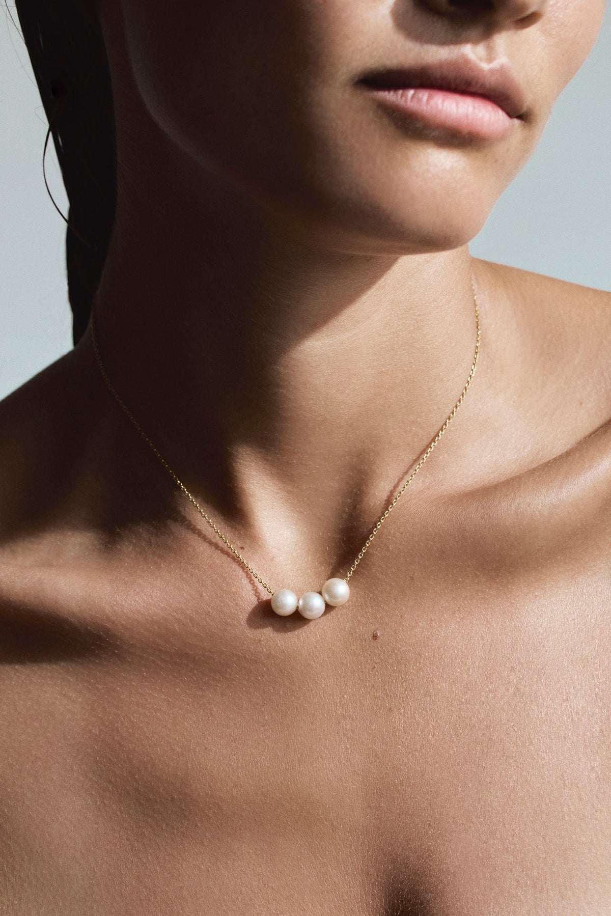 Close-up of three lustrous South Sea pearls suspended from a fine 18K solid gold chain