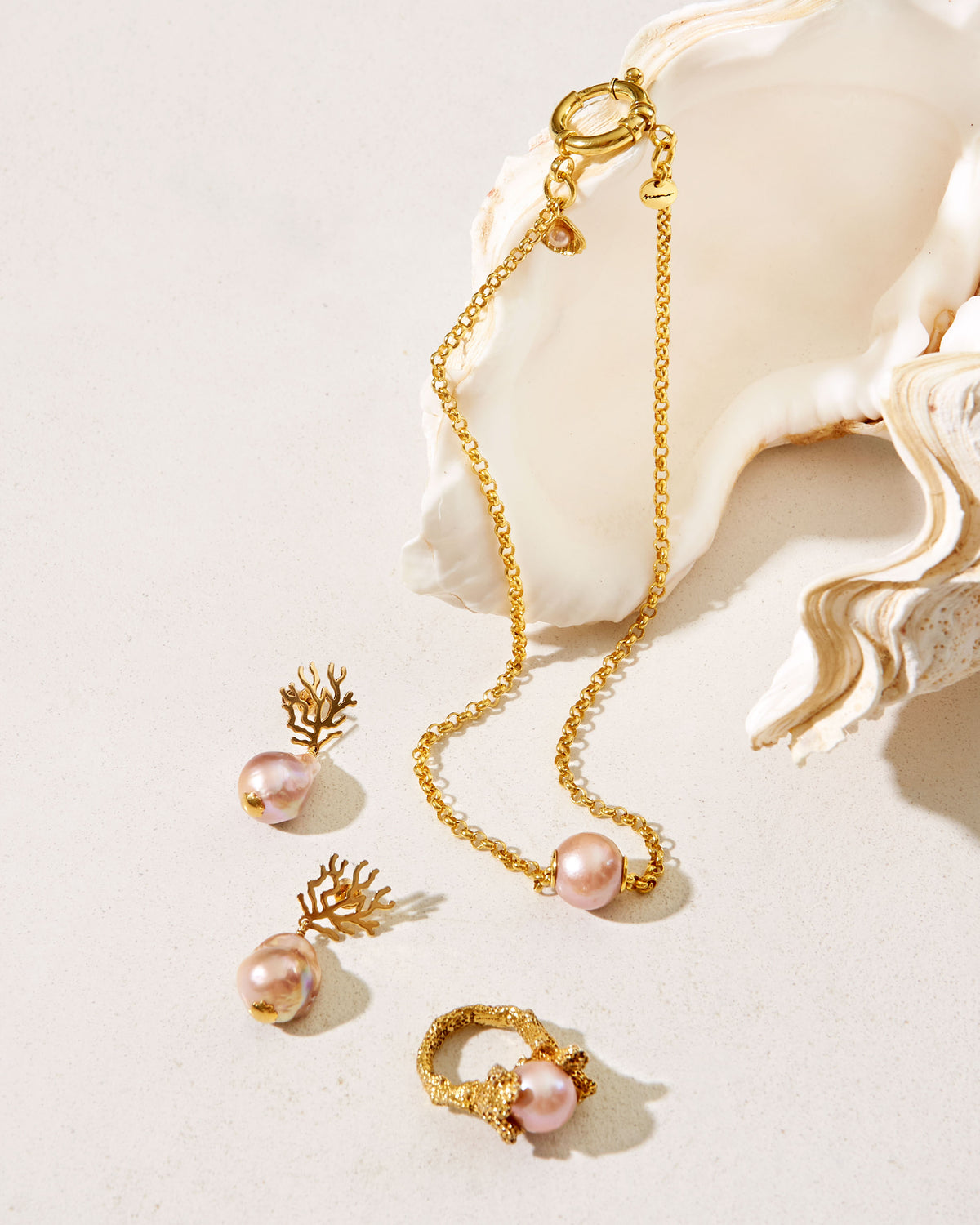 Close-up of Paul et Virginie gold necklace with white pearl, nautical clasp and shell charm