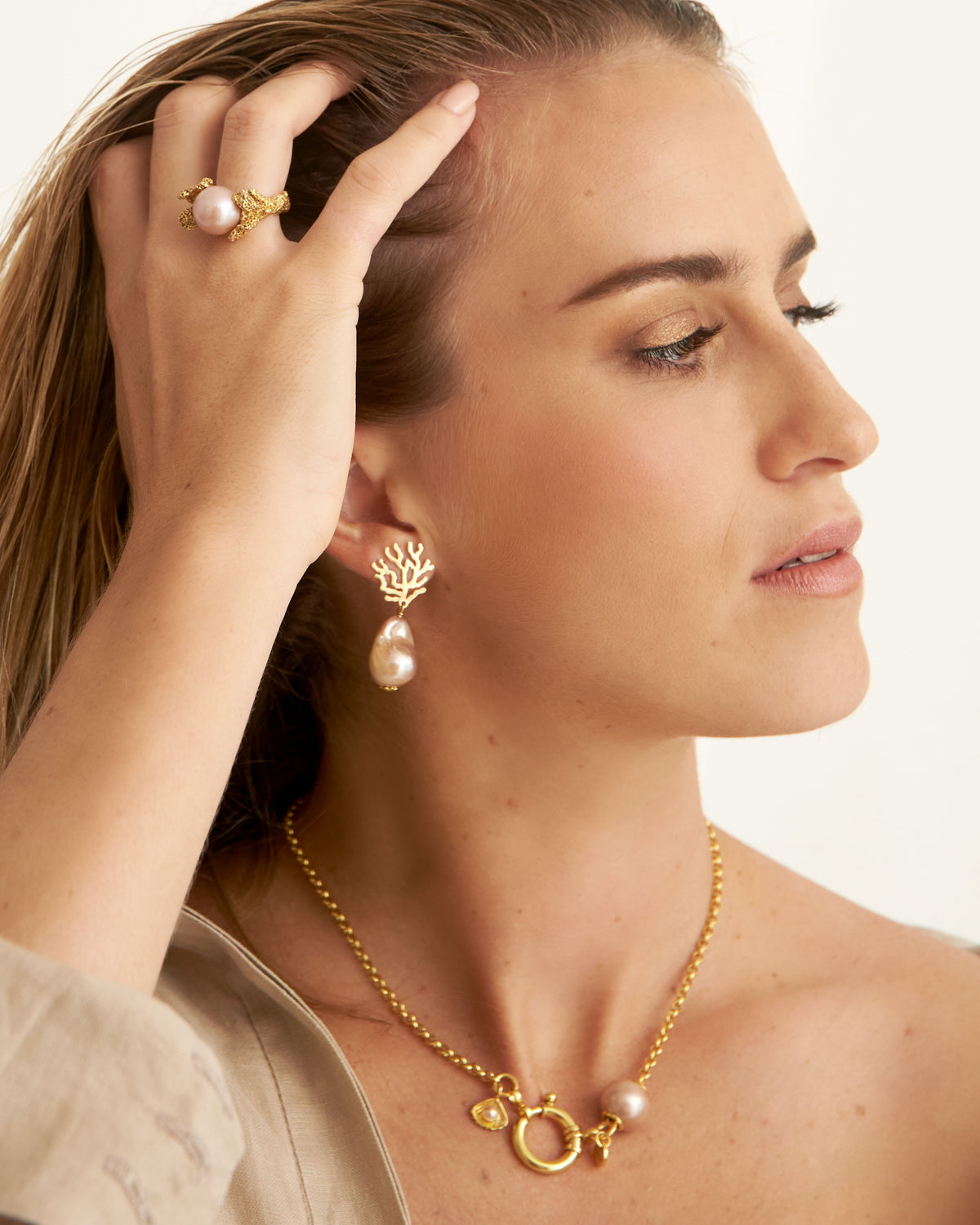 Close-up of Paul et Virginie gold necklace with white pearl, nautical clasp and shell charm