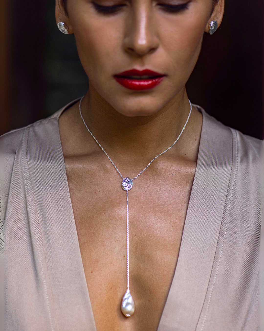 Close-up of sterling silver spiral shell necklace with white freshwater baroque pearl by Oceano Jewe